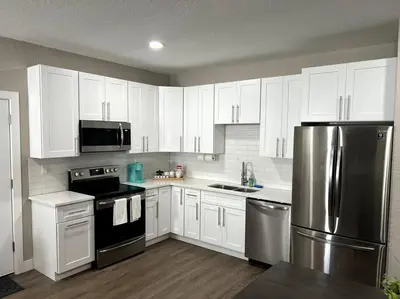 a kitchen with white cabinets and a stainless steel refrigerator at Modern studio in the heart of Brighton! in Brighton