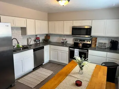 a kitchen with white cabinets and a table with a vase of flowers at Spacious Westminster 2bd/1ba in Westminster