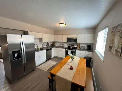 a kitchen with a table and a stainless steel refrigerator at Spacious Westminster 2bd/1ba in Westminster