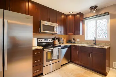 a kitchen with wooden cabinets and a stainless steel refrigerator at Cozy Getaway Retreat - 4BR - Northglenn in Northglenn