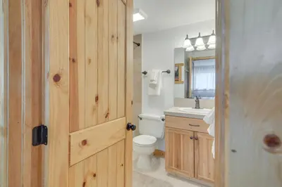 a bathroom with a wooden door and a toilet and sink at Convenient Winter Park Condo - 3 Mi to Resort! in Winter Park