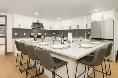 a large white kitchen with a long table with chairs at Modern luxury mountain house in Fraser
