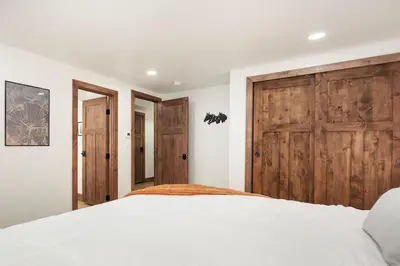 a bedroom with a large bed and wooden doors at Stylish Mountain getaway in Fraser
