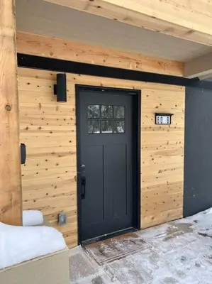 a wooden building with a black door in it at Stylish Mountain getaway in Fraser