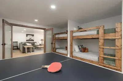 a room with a ping pong table and bunk beds at Stylish Mountain getaway in Fraser