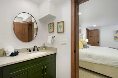 a bathroom with a sink and a mirror and a bed at Stylish Mountain getaway in Fraser