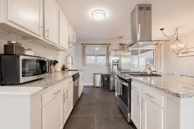 a large kitchen with white cabinets and a microwave at Light-filled retreat w hot tub & firepit in Denver