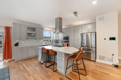 a kitchen with white cabinets and a island with bar stools at Walk to Broncos Stadium Hot tub & Rooftop in Denver