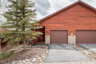 a red house with two garage doors and a tree at Lookout Ridge 45 by Great Western Lodging in Dillon