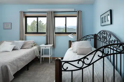 a bedroom with two beds and two windows at Lookout Lodge in Wondervu home in Nederland
