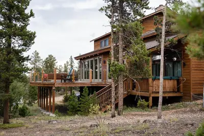 a house with a wrap around deck in the woods at Lookout Lodge in Wondervu home in Nederland