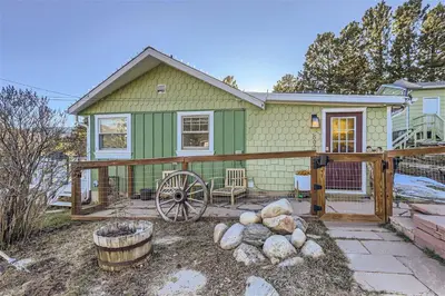 a green house with a wooden fence and a yard at Nederland Mountain Haven bungalow in Nederland