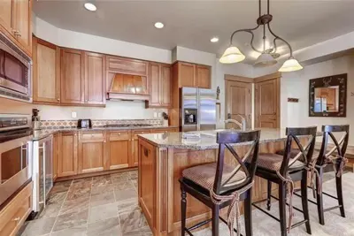 a kitchen with wooden cabinets and a island with bar stools at Ski In, Ski Out 3 Bedroom At Lone Eagle In River Run in Dillon