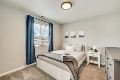 a bedroom with a bed with blue curtains and a window at Berthoud Home with Fire Pit, Close to Lake Loveland! in Berthoud