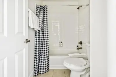a white bathroom with a toilet and a bath tub at Modern Elegance - Pool Table - Walkable Area in Aurora