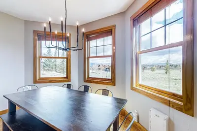 a dining room with a table and chairs and windows at Mountain Sky Retreat in Granby