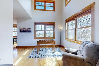 a living room with a ping pong table and windows at Mountain Sky Retreat in Granby