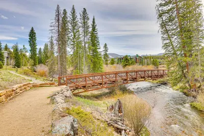 a wooden bridge over a river in a forest at Walk to Dtwn Fraser Retreat with Hot Tub and Views! in Winter Park