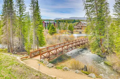 a wooden bridge over a river with a house in the background at Walk to Dtwn Fraser Retreat with Hot Tub and Views! in Winter Park