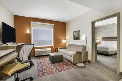 a hotel room with a bed and a couch and a desk at Home2 Suites By Hilton Aurora Medical Center Denver in Aurora