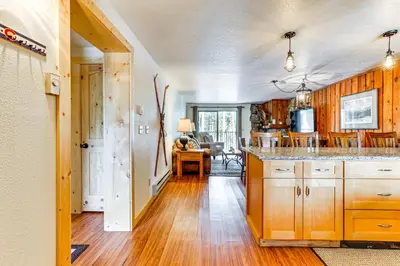 a kitchen with wooden cabinets and a dining room at Winter Park Condo with Resort Shuttle On-Site! in Winter Park