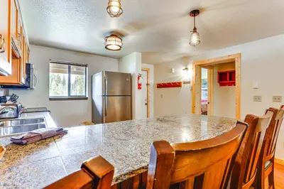 a kitchen with a large counter with chairs and a refrigerator at Winter Park Condo with Resort Shuttle On-Site! in Winter Park