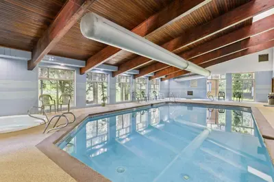 a large swimming pool in a house with a wooden ceiling at Winter Park Condo with Resort Shuttle On-Site! in Winter Park