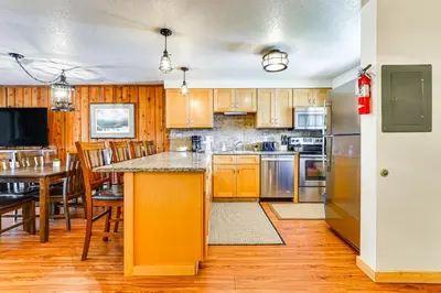 a kitchen with wooden cabinets and a table with chairs at Winter Park Condo with Resort Shuttle On-Site! in Winter Park