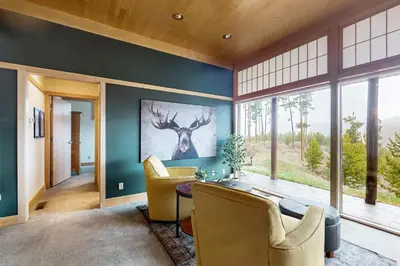 a living room with a table and a deer painting on the wall at Mountain Minka in Grand Lake