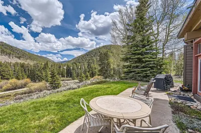 a patio with a table and chairs and a field at 2024 Homestead condo in Keystone
