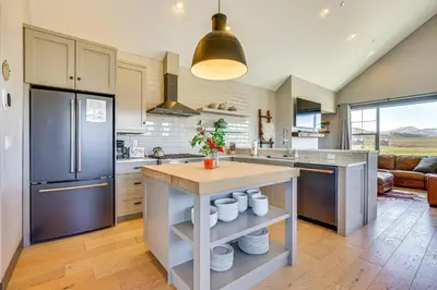 a kitchen with a refrigerator and a table with dishes at Hot Tub and Mtn Views Townhome in Granby! in Granby