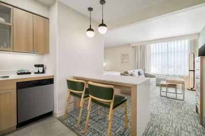 a kitchen and living room with a counter and chairs at Homewood Suites By Hilton Thornton Denver in Thornton