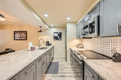 a kitchen with gray cabinets and marble counter tops at 2509 Saints John condo in Keystone