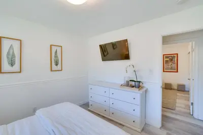 a white bedroom with a bed and a tv on a wall at Covered Patio and Fire Pit Centennial Home! in Centennial