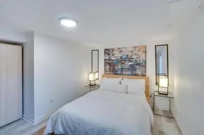 a white bedroom with a bed and two lamps at Sleek and Central Centennial Apartment with Fireplace! in Centennial