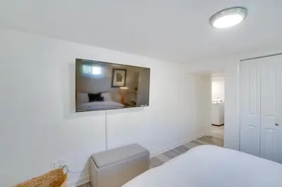a white bedroom with a bed and a tv on the wall at Sleek and Central Centennial Apartment with Fireplace! in Centennial