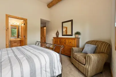a bedroom with a bed and a chair and a mirror at 103 Antler Way at Lakota townhouse in Winter Park