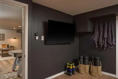 a room with a tv on a wall with boots at NEW Modern, Luxury Home with Hot Tub, Gym, Sauna, and 12 Minutes to Denver in Arvada