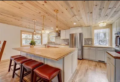 a kitchen with white cabinets and a large island with bar stools at House of The Rising Sun in Bailey