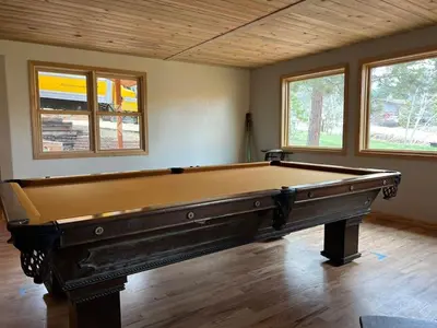 a large pool table in a room with windows at House of The Rising Sun in Bailey