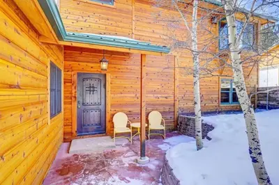 a log cabin with two chairs and a door at House of The Rising Sun in Bailey