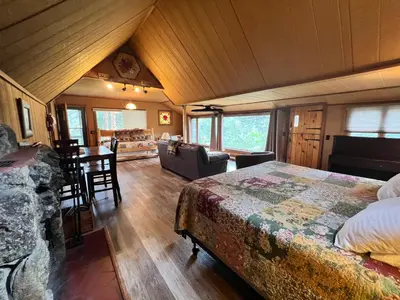 a bedroom with a bed and a living room and a table at Rose Den - Romantic Mountain Cabin with Views! in Estes Park