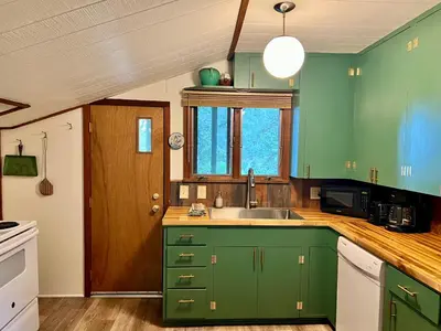 a kitchen with green cabinets and a sink at Rose Den - Romantic Mountain Cabin with Views! in Estes Park