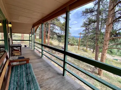 a room with a bench on a porch with trees at Rose Den - Romantic Mountain Cabin with Views! in Estes Park