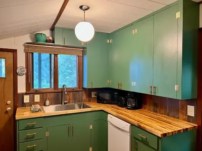 a kitchen with green cabinets and a sink at Rose Den - Romantic Mountain Cabin with Views! in Estes Park