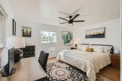 a bedroom with a bed with a desk and a ceiling fan at Natural Light, High-Vaulted Ceilings Apartment and Garage in Lakewood