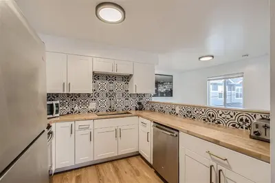 a kitchen with white cabinets and a window at Natural Light, High-Vaulted Ceilings Apartment and Garage in Lakewood