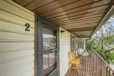 a porch with two chairs on a house at Natural Light, High-Vaulted Ceilings Apartment and Garage in Lakewood