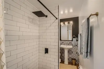 a white bathroom with a sink and a mirror at Natural Light, High-Vaulted Ceilings Apartment and Garage in Lakewood