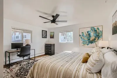 a bedroom with a bed with a ceiling fan and a desk at Natural Light, High-Vaulted Ceilings Apartment and Garage in Lakewood